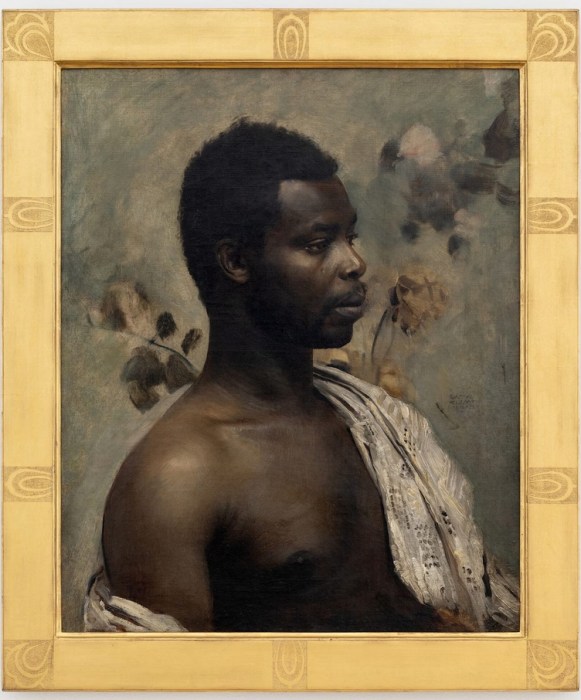 Oil on canvas painting, Portrait of Prince William Nii Nortey Dowuona, Bildnis eines Negers (Head of a Negro), by Gustav Klimt, 1897. A three-quarter portrait of a Black man with a mustache and short hair, dressed in a dark European suit with a white collar. He looks directly at the viewer with a calm, dignified expression against a dark background with subtle, muted floral undertones. Klimt estate stamp on verso. Natter 245.